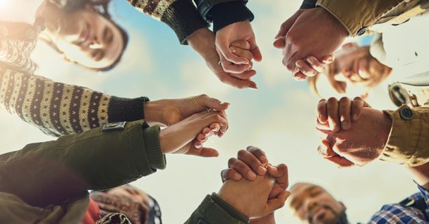 Shot of a group of friends putting their hands together in prayer
